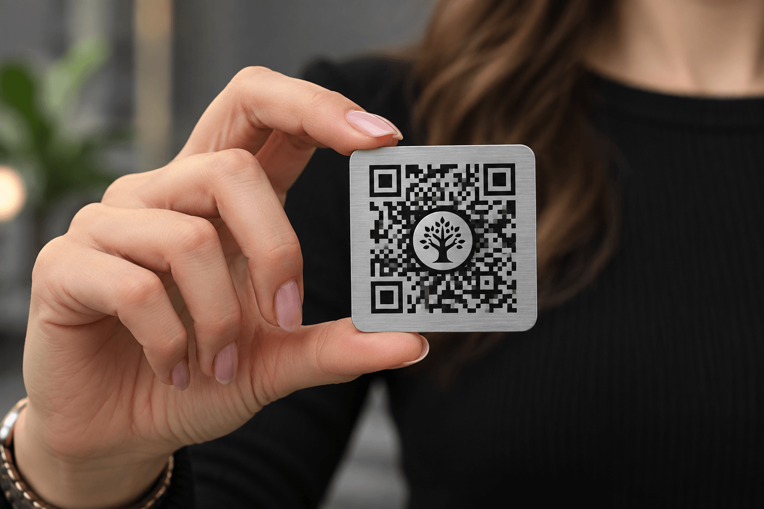 Серебристая QR-табличка с символом дерева Наследие в руке